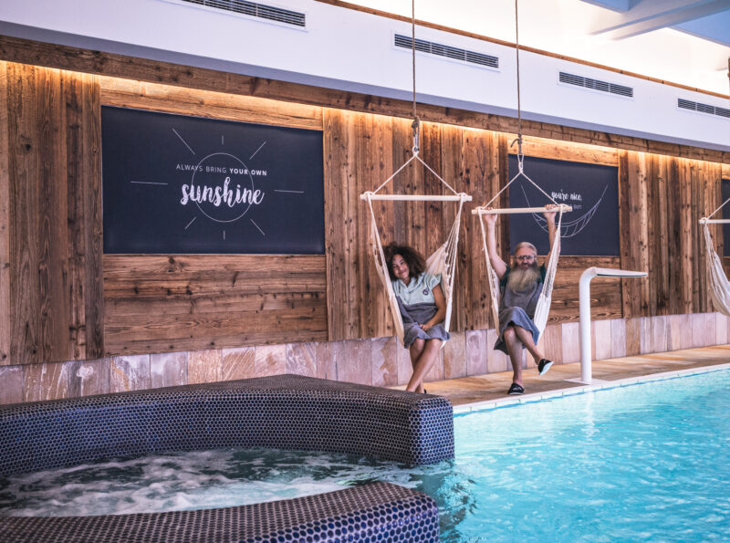 Couple sitting in hanging chairs next to the indoor pool and the integrated whirlpool