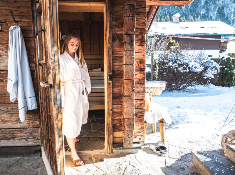 girl walking out of the alpine hut sauna in the garde