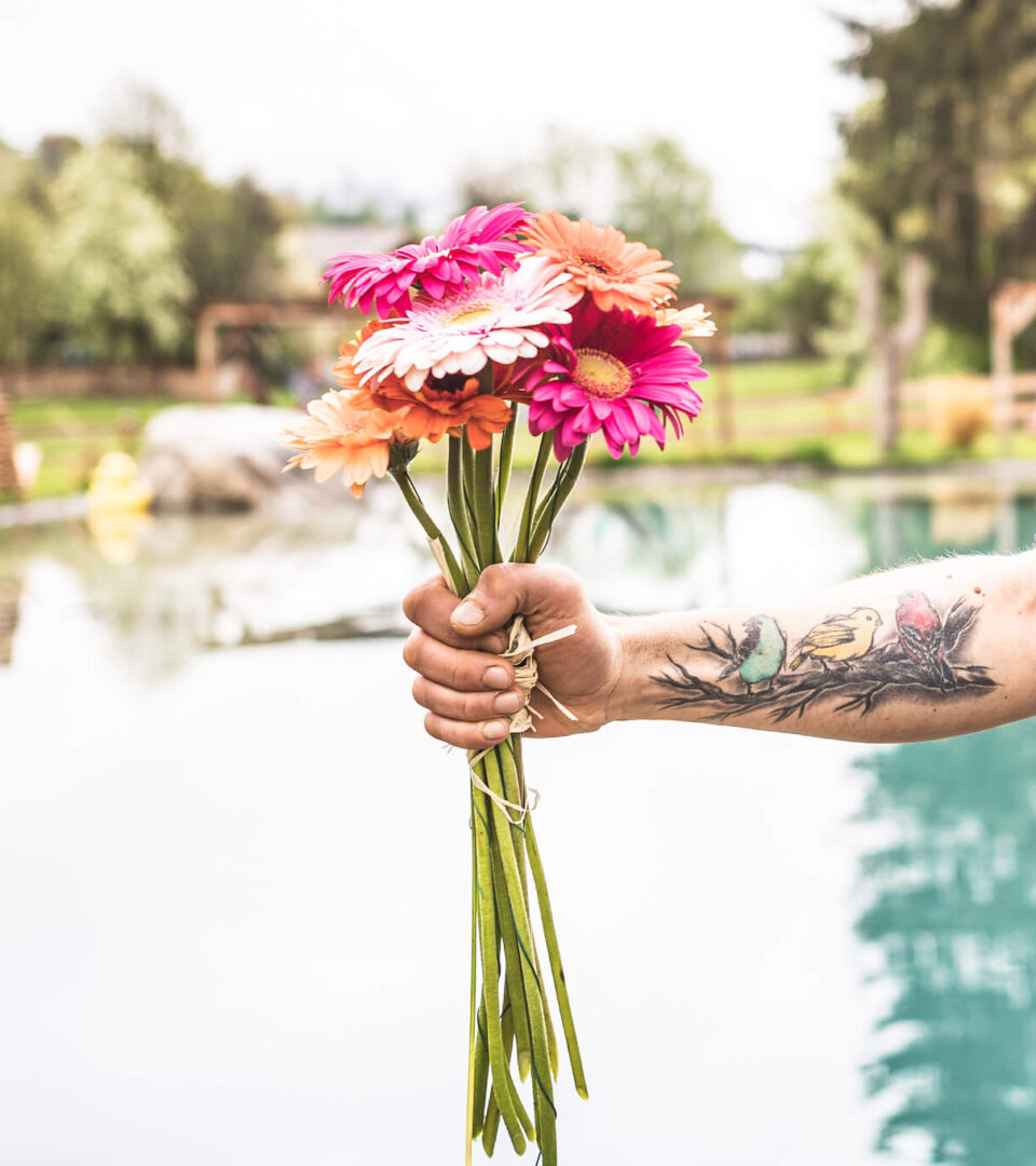 Tätovierte Hand hält einen bunten Blumenstrauß
